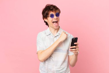 Cep telefonlu genç adam kendini mutlu hissediyor ve bir meydan okumayla yüzleşiyor ya da kutluyor