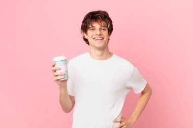 Elinde kahveyle mutlu bir şekilde gülümseyen genç bir adam.