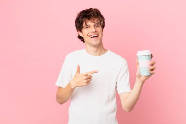 Kahveli genç adam neşeyle gülümsüyor, mutlu hissediyor ve bir tarafı işaret ediyor.