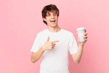 Elinde kahve olan genç adam heyecanlı ve şaşırmış görünüyor.
