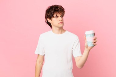 Kahveli genç bir adam üzgün, üzgün ya da kızgın ve yana bakıyor.