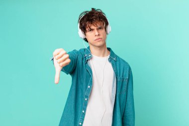 Kulaklıklı genç adam kızıyor, baş parmağını kaldırıyor.