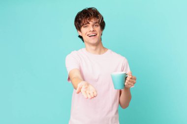 Elinde kahve fincanı olan genç adam mutlu bir şekilde gülümsüyor ve bir konsept sunuyor.