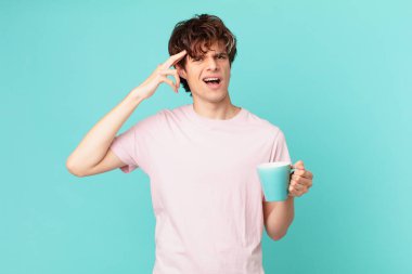 Elinde kahve fincanı olan kafası karışmış ve kafası karışmış genç adam, senin deli olduğunu gösteriyor.