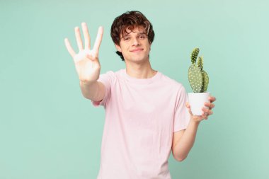 Kaktüslü genç adam gülümsüyor ve arkadaş canlısı görünüyor, dört numarayı gösteriyor.