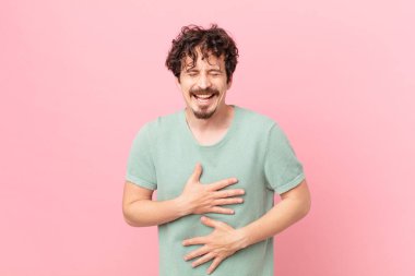 Genç yakışıklı adam komik bir şakaya yüksek sesle gülüyor.