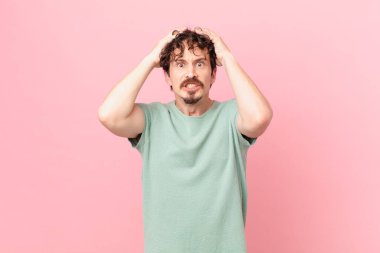 Genç ve yakışıklı adam stresli, endişeli ya da korkmuş, elleri başının üstünde.
