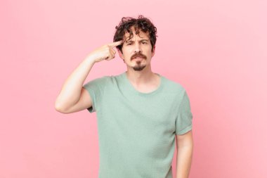 Genç yakışıklı adam kafası karışık ve şaşkın hissediyor, deli olduğunu gösteriyor.