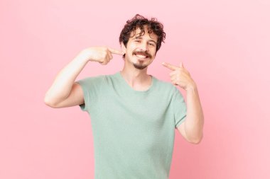 Genç ve yakışıklı bir adam, kendine güvenerek gülümsüyor.