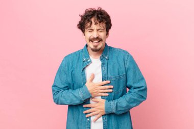 Genç yakışıklı adam komik bir şakaya yüksek sesle gülüyor.