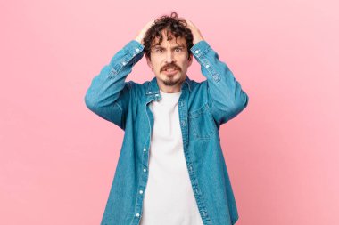 Genç ve yakışıklı adam stresli, endişeli ya da korkmuş, elleri başının üstünde.