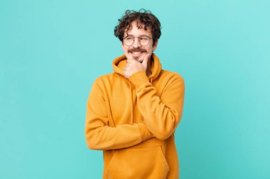 Genç ve yakışıklı bir adam mutlu, kendinden emin bir ifadeyle gülümsüyor.