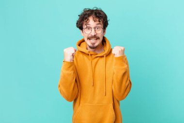 Genç yakışıklı adam şokta, gülüyor ve başarıyı kutluyor.