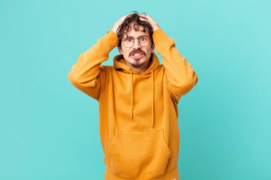 Genç ve yakışıklı adam stresli, endişeli ya da korkmuş, elleri başının üstünde.