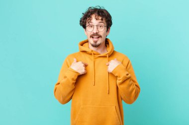 Genç yakışıklı adam mutlu hissediyor ve heyecanla kendini işaret ediyor.