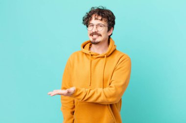 Genç yakışıklı adam neşeyle gülümsüyor, mutlu hissediyor ve bir konsept gösteriyor.