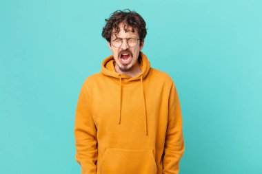 Genç yakışıklı adam agresif bir şekilde bağırıyor, çok sinirli görünüyor.