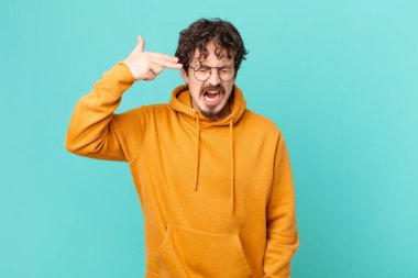 Genç yakışıklı adam mutsuz ve stresli görünüyor, intihar jesti silah işareti yapıyor.