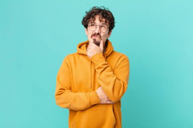 Genç yakışıklı adam düşünüyor, kuşkulu ve şaşkın hissediyor.