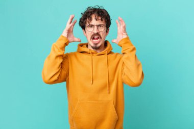 Genç yakışıklı adam ellerini havaya kaldırarak bağırıyor.