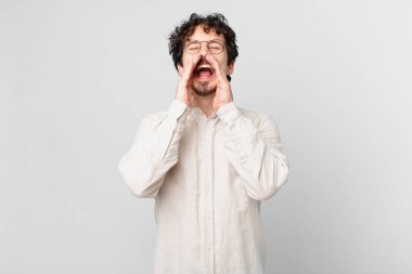 Genç yakışıklı adam mutlu hissediyor, elleri ağızda bağırıyor.