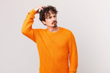 Kafası karışmış, kafası karışmış, kaşınan genç yakışıklı bir adam.