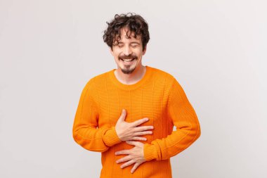 Genç yakışıklı adam komik bir şakaya yüksek sesle gülüyor.