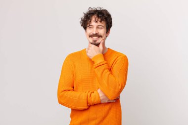 Genç ve yakışıklı bir adam mutlu, kendinden emin bir ifadeyle gülümsüyor.