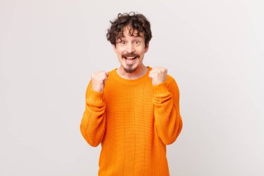 Genç yakışıklı adam şokta, gülüyor ve başarıyı kutluyor.