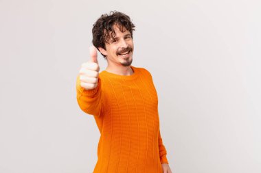 Genç yakışıklı adam gururlu, olumlu gülümsüyor.