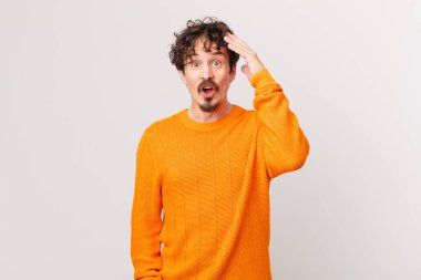 Genç yakışıklı adam mutlu, şaşkın ve şaşkın görünüyor.