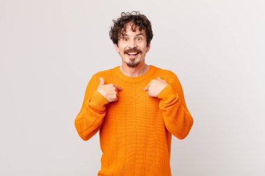 Genç yakışıklı adam mutlu hissediyor ve heyecanla kendini işaret ediyor.