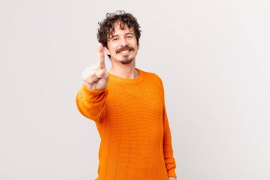 Genç yakışıklı adam gururla gülümsüyor ve kendinden emin bir numara oluyor.