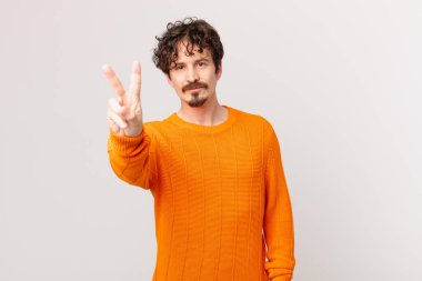 Genç yakışıklı adam gülümsüyor ve arkadaş canlısı görünüyor.