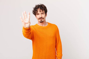 Genç yakışıklı adam gülümsüyor ve arkadaş canlısı görünüyor, dört numarayı gösteriyor.