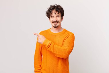Genç yakışıklı adam neşeyle gülümsüyor, mutlu hissediyor ve bir tarafı işaret ediyor.