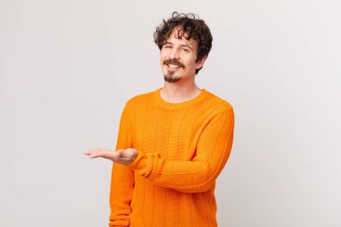 Genç yakışıklı adam neşeyle gülümsüyor, mutlu hissediyor ve bir konsept gösteriyor.