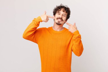 Genç ve yakışıklı bir adam, kendine güvenerek gülümsüyor.