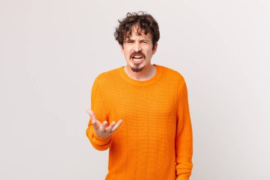 Genç yakışıklı adam sinirli, sinirli ve sinirli görünüyor.