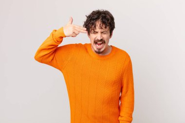 Genç yakışıklı adam mutsuz ve stresli görünüyor, intihar jesti silah işareti yapıyor.
