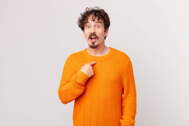 Şok olmuş ve ağzı açık, kendini işaret eden genç yakışıklı bir adam.
