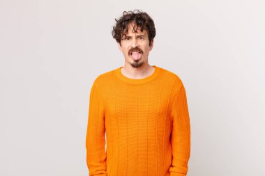 Genç yakışıklı adam iğreniyor, sinirleniyor ve dilini çıkarıyor.