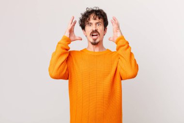 Genç yakışıklı adam ellerini havaya kaldırarak bağırıyor.