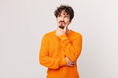 Genç yakışıklı adam düşünüyor, kuşkulu ve şaşkın hissediyor.