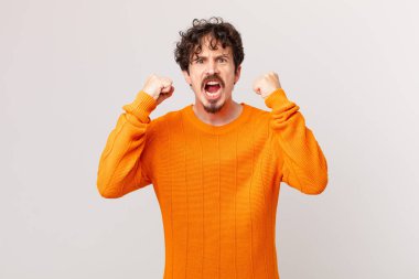 Genç yakışıklı adam sinirli bir ifadeyle agresif bir şekilde bağırıyor.