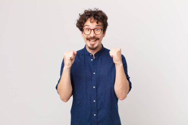 Genç yakışıklı adam şokta, gülüyor ve başarıyı kutluyor.