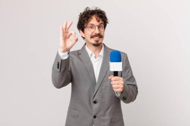 Genç gazeteci kendini mutlu hissediyor, iyi bir jestle onaylıyor.