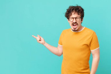 Genç yakışıklı adam agresif bir şekilde bağırıyor, çok sinirli görünüyor.