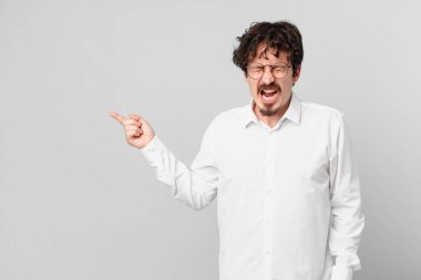 Genç yakışıklı adam agresif bir şekilde bağırıyor, çok sinirli görünüyor.