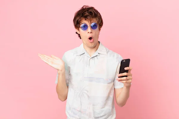 Молодой Человек Сотовым Телефоном Выглядит Удивленным Шокированным Челюстью Упал Держа — стоковое фото